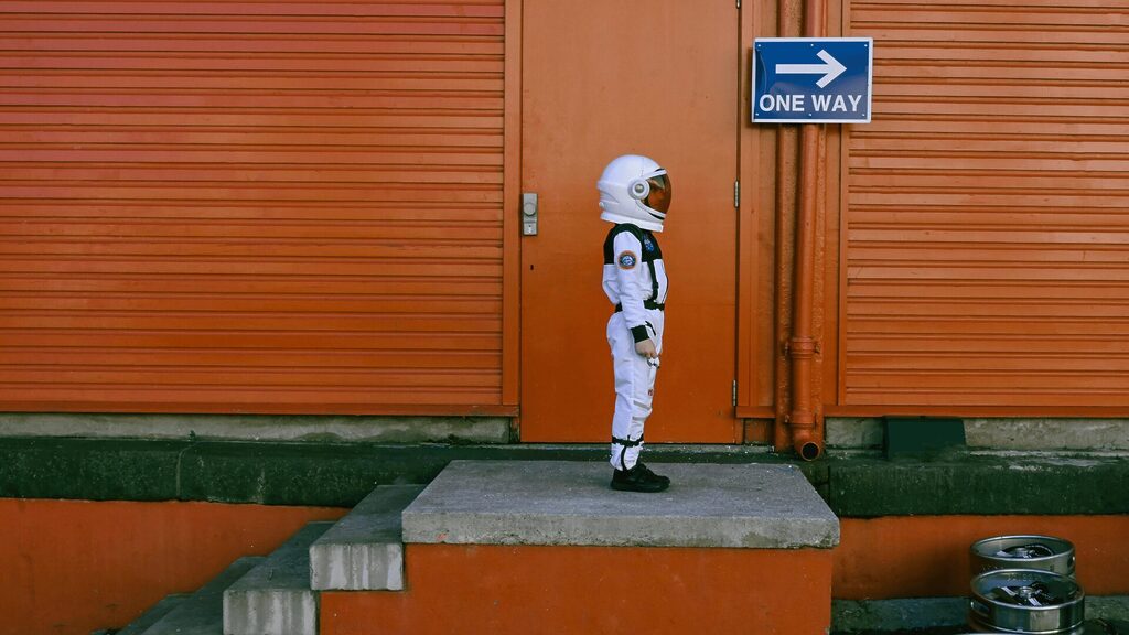 Little Astronaut stood in from of a red building by Jolanta Pakla-Plebankiewicz