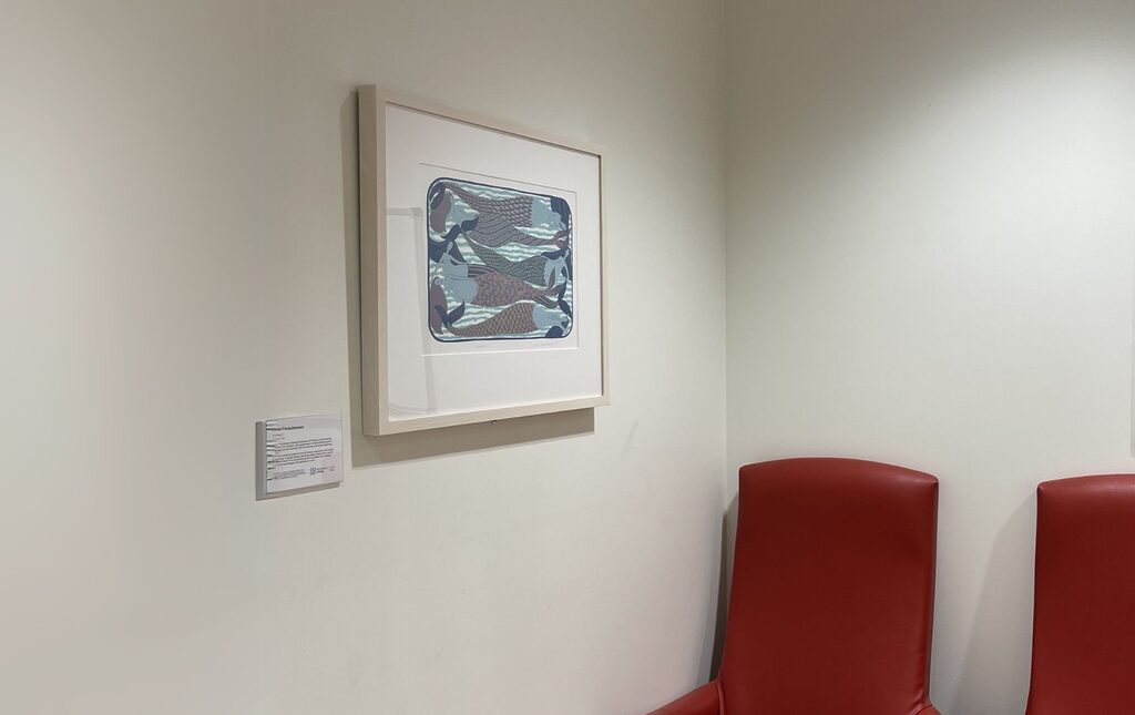 artwork and label on the wall at the royal edinburgh building's ect waiting room with two red chairs beside it