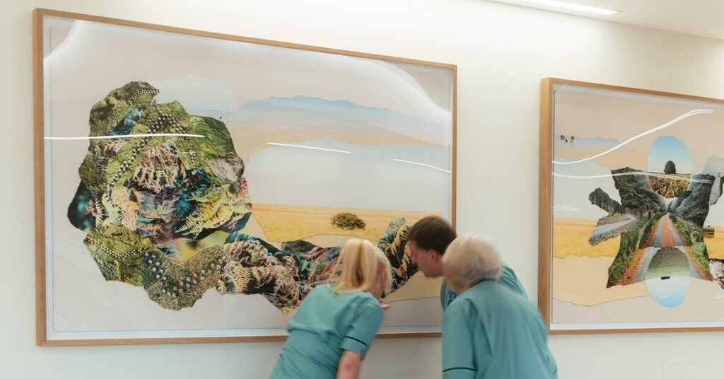 3 staff looking closely at a piece of artwork