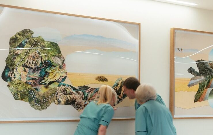 3 staff looking closely at a piece of artwork
