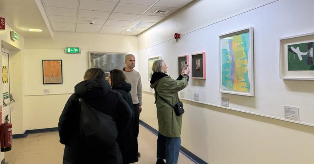 people looking at art and photographing it on phone