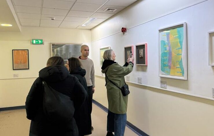 people looking at art and photographing it on phone